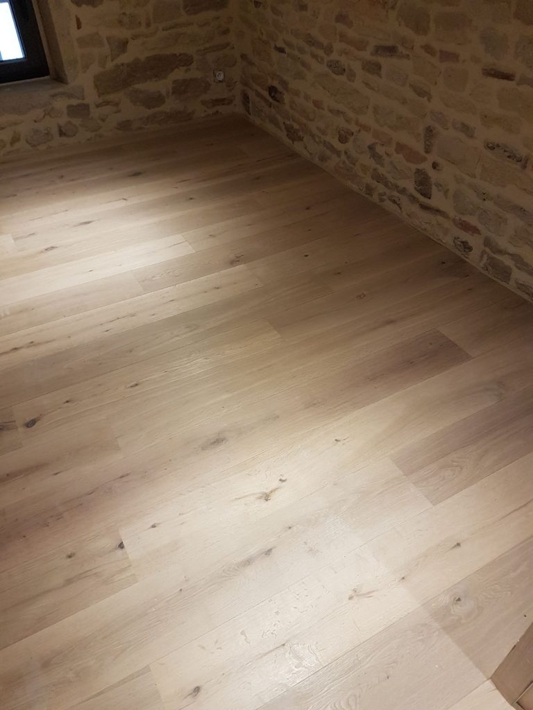 Parquet contrecollé chêne rustique verni naturel marque Parador posé dans une maison en pierres dorées à Valsonne