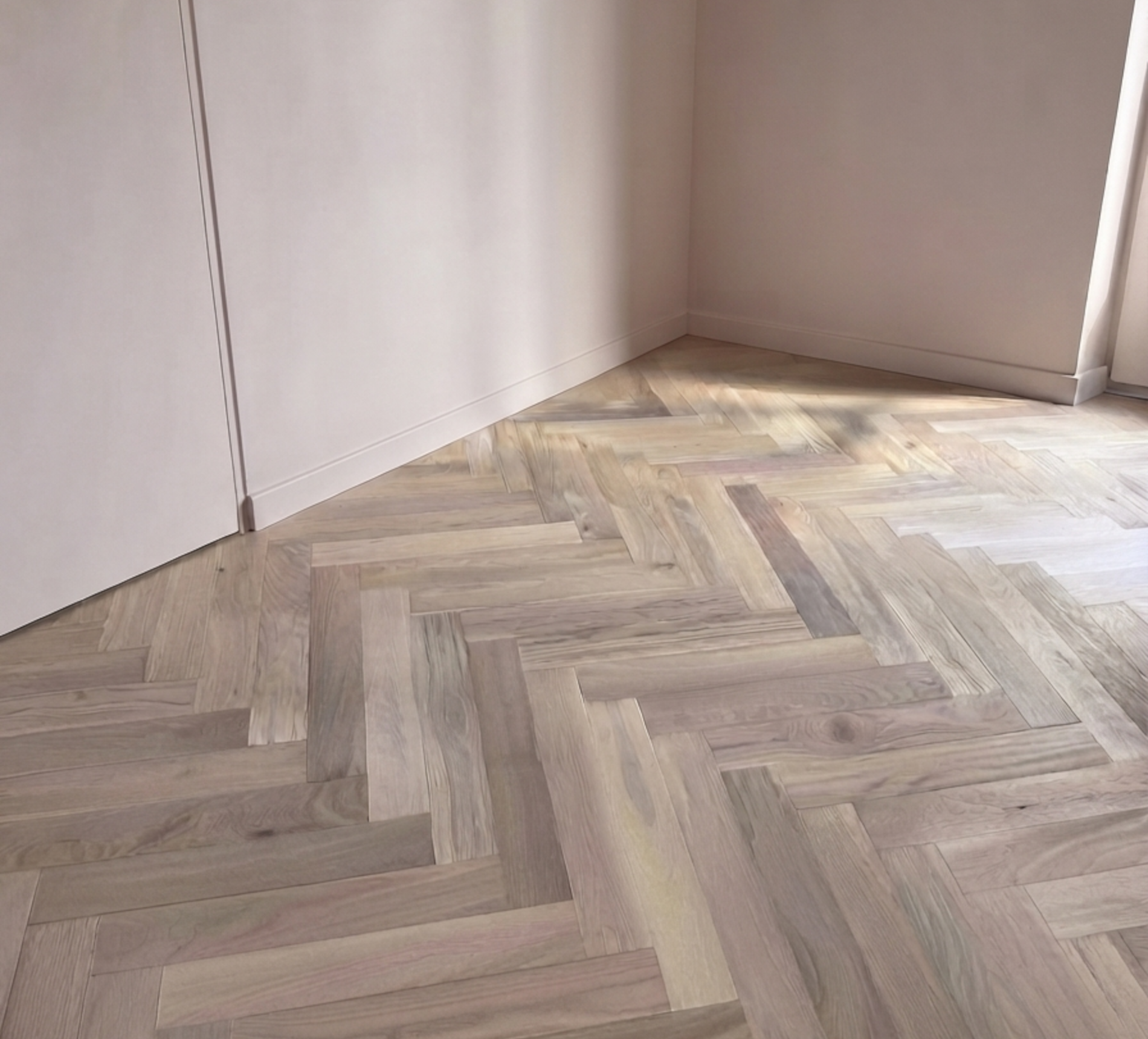 Parquet chêne verni aspect bois brut bâtons rompus dans pièce pein te en rose poudré à Champagne au Mont d'Or