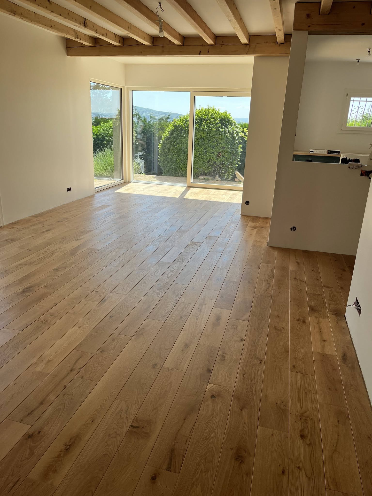 Magnifique parquet massif français rustique huilé naturel posé à l'anglaise dans une pièce de vie lumineuse avec baies vitrées